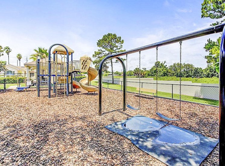 Playground equipment with a slide and a separate swing set with two swings.
