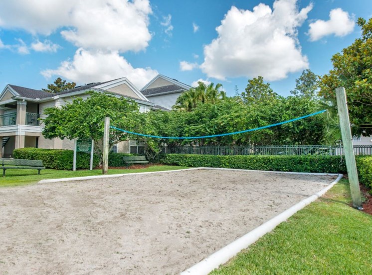 Sand Volleyball Court Surrounded by Trees and Shrubs with Building Exterior in The Background
