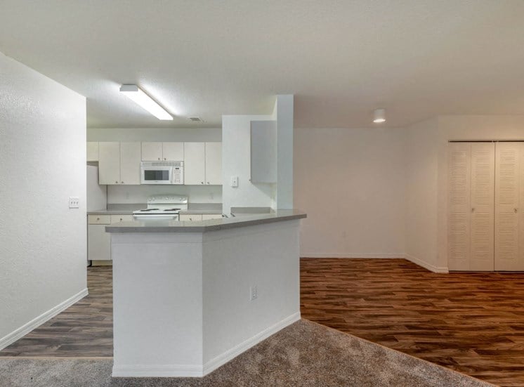 Open Kitchen with Grey Counters White Appliances and Cabinets with Breakfast Bar Next to Dining Room with Hardwood Style Flooring with Sliding Closet