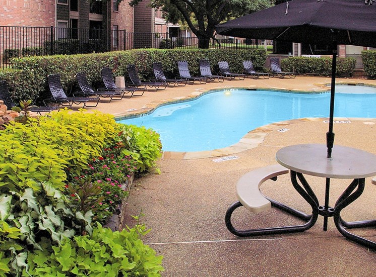 Swimming pool with lounge seating, picnic table with umbrella and building exteriors