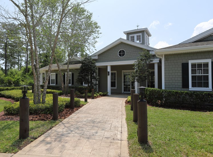 The Management Office is a nautical styled building with shingle siding in dark grey and blue colors. The brick paver walkway up to the front doors are lined with wooden harbor posts.