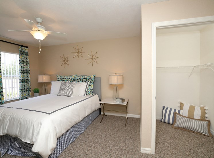 The Bedroom is a comfortable space with a large bed centered on the main wall. A large window brings plenty of natural light into the room. The carpeted flooring continues into the walk-in closet.