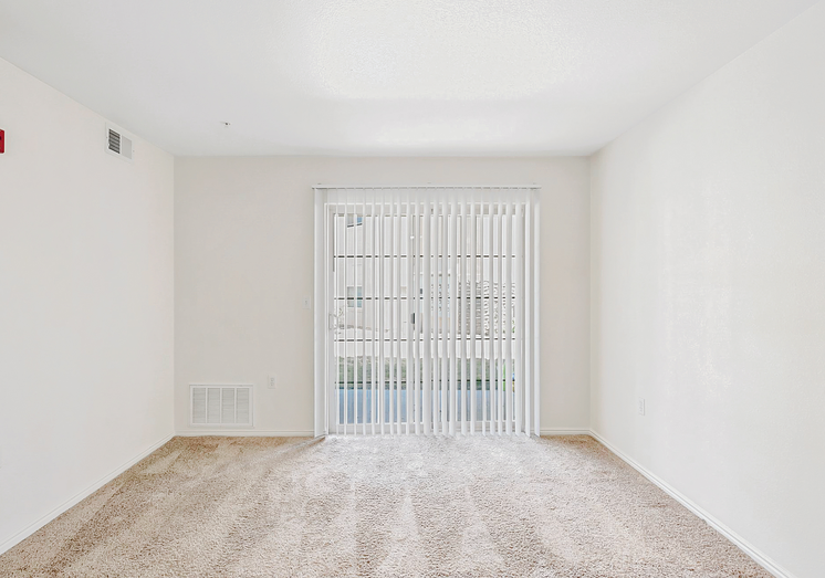 Carpeted living room facing sliding windowed door