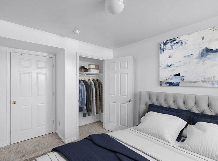Virtually staged bedroom with bed, wall art, carpet and closet with hung clothing