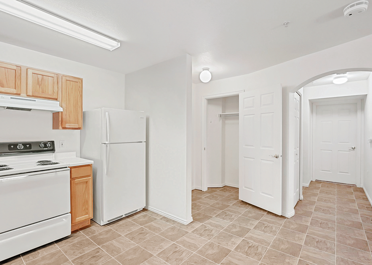 View of kitchen and entryway with white appliances and tiled floor