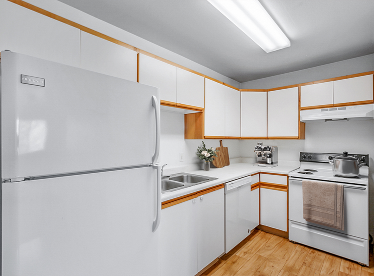 Virtually staged kitchen with pot on stove, white appliances and wooden floors