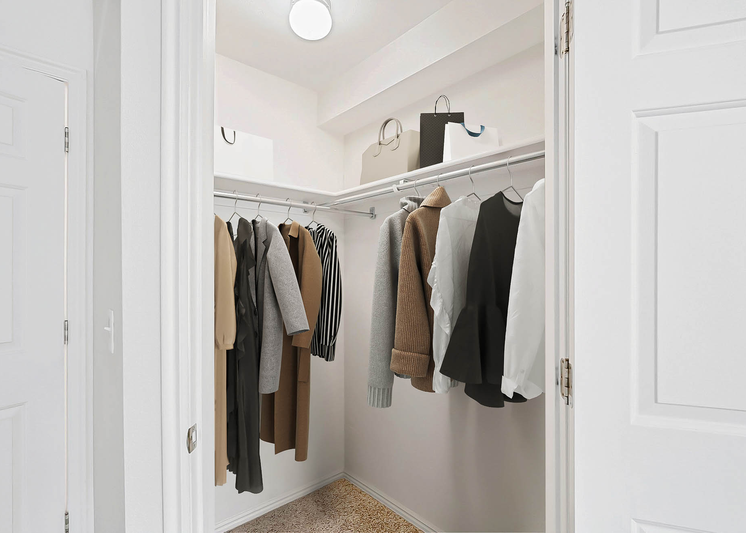 Walk-in closet with white poles and shelving and clothes hanging