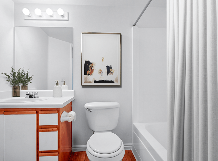 Virtually staged bathroom with shower curtain, wall art, white sink and wooden cabinets