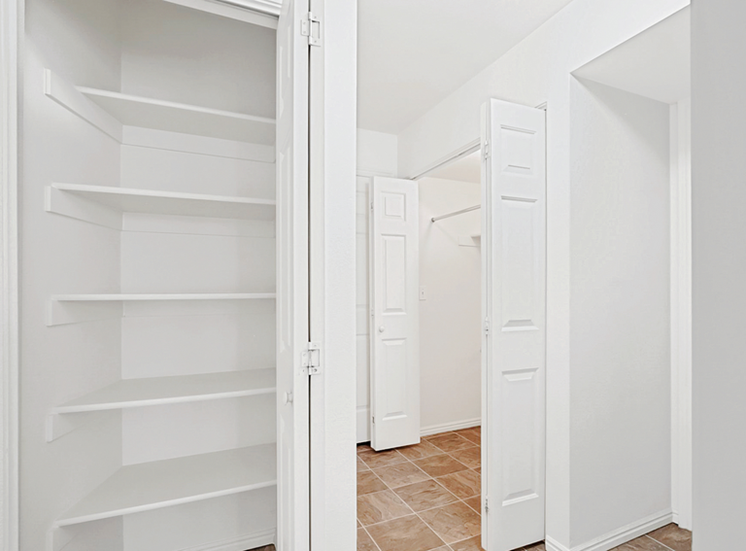 View of hallway with laundry machines and shelved linen closet