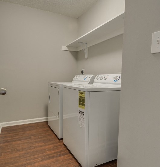 Laundry room with white washer and dryer on wood style floor