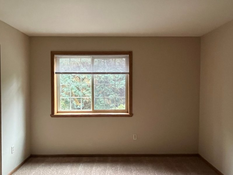 A room with a window and a carpeted floor.