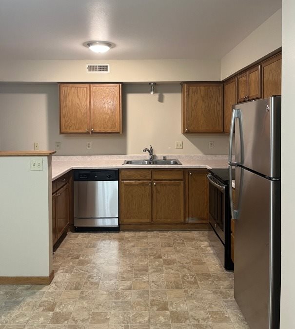A kitchen with a refrigerator, sink, and cabinets.