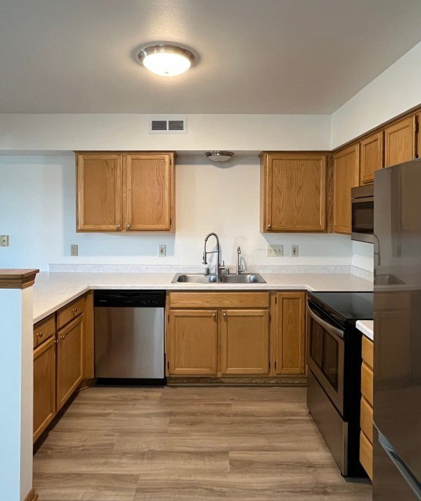 A kitchen with wooden cabinets and a stainless steel dishwasher.