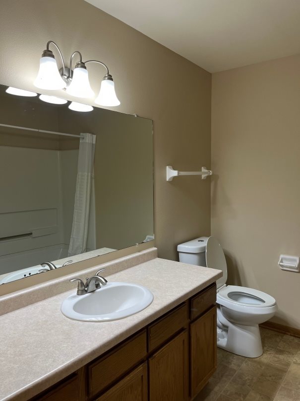 A bathroom with a sink, toilet, and mirror.