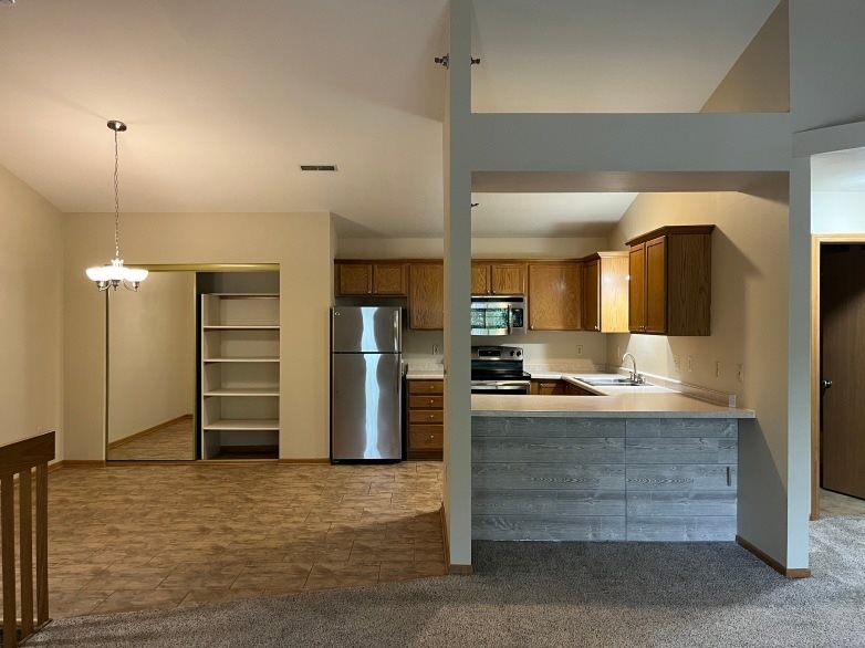 A kitchen with a refrigerator, sink, and cabinets.