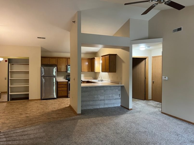 A kitchen area with a refrigerator, sink, and cabinets.
