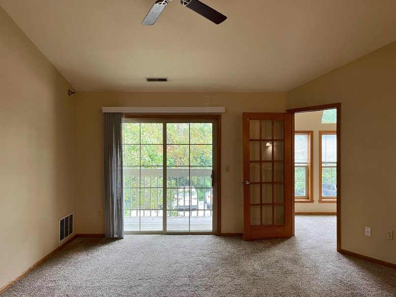 A room with a ceiling fan and carpeted floor.