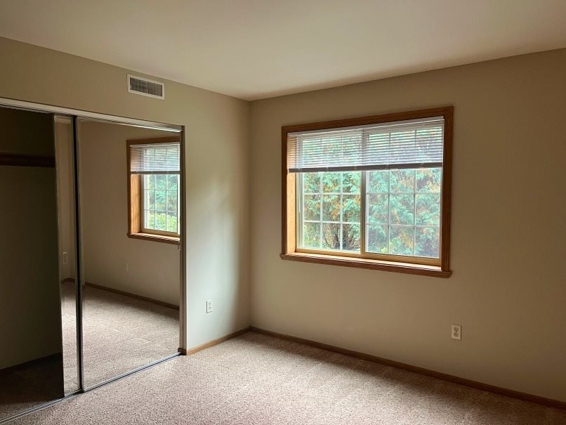 A room with a carpeted floor and two windows.