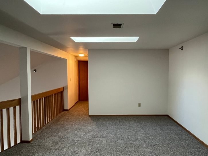 A room with a carpeted floor and a wooden door.