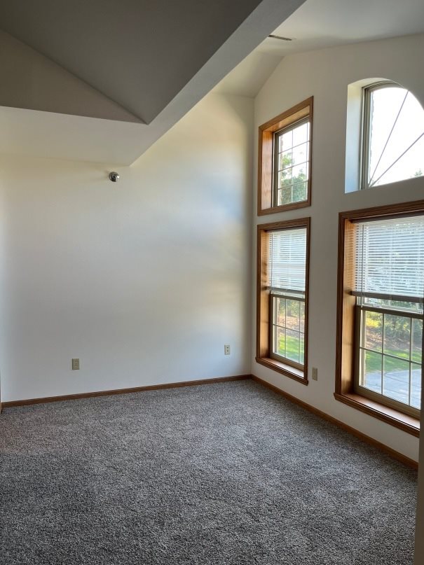 A room with a carpeted floor and a window with blinds.