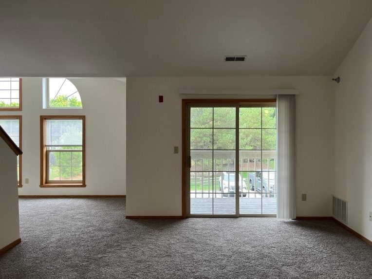 A room with a carpeted floor and a sliding glass door leading to a patio.