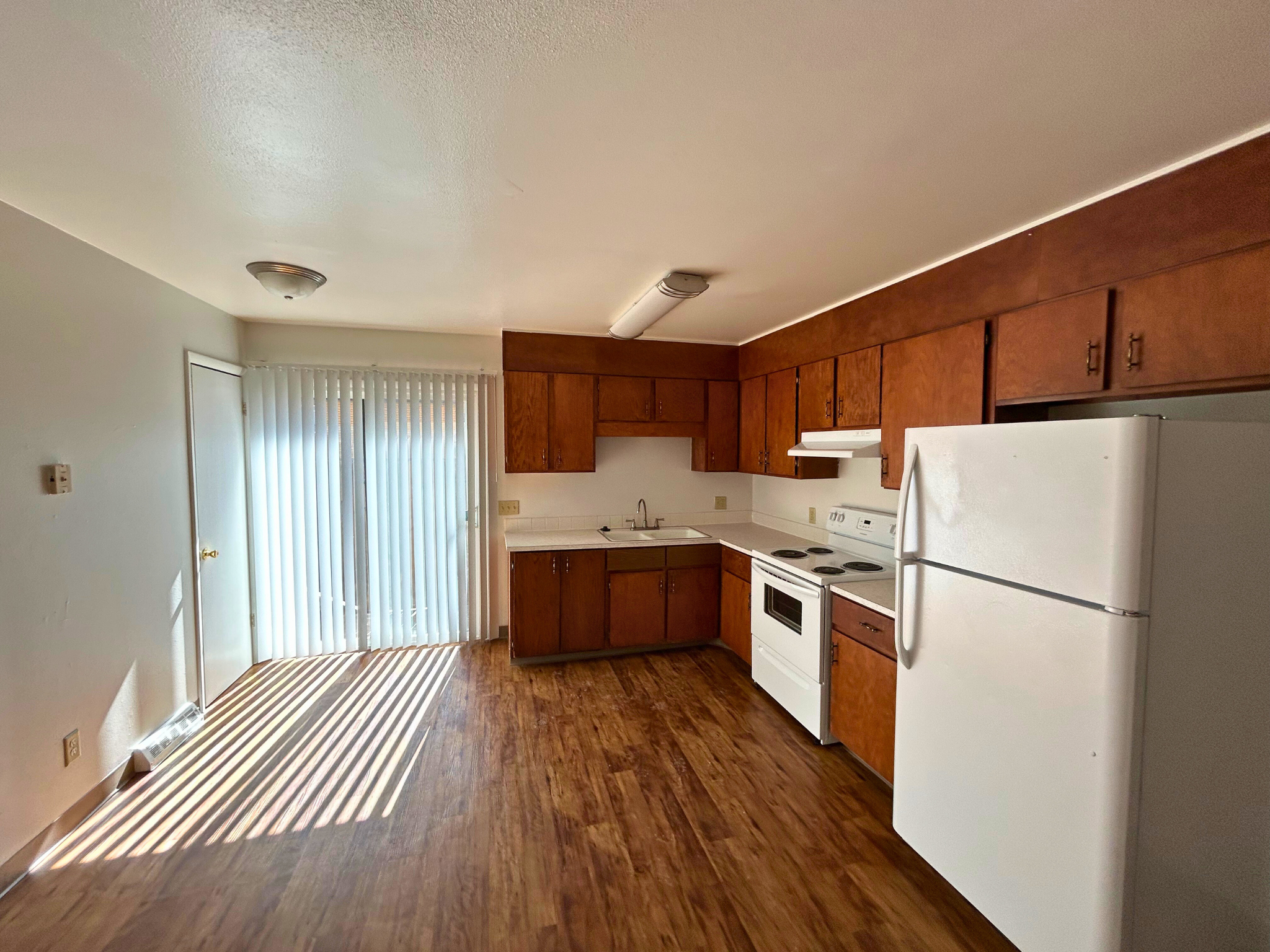 A kitchen with white appliances and wooden cabinets.