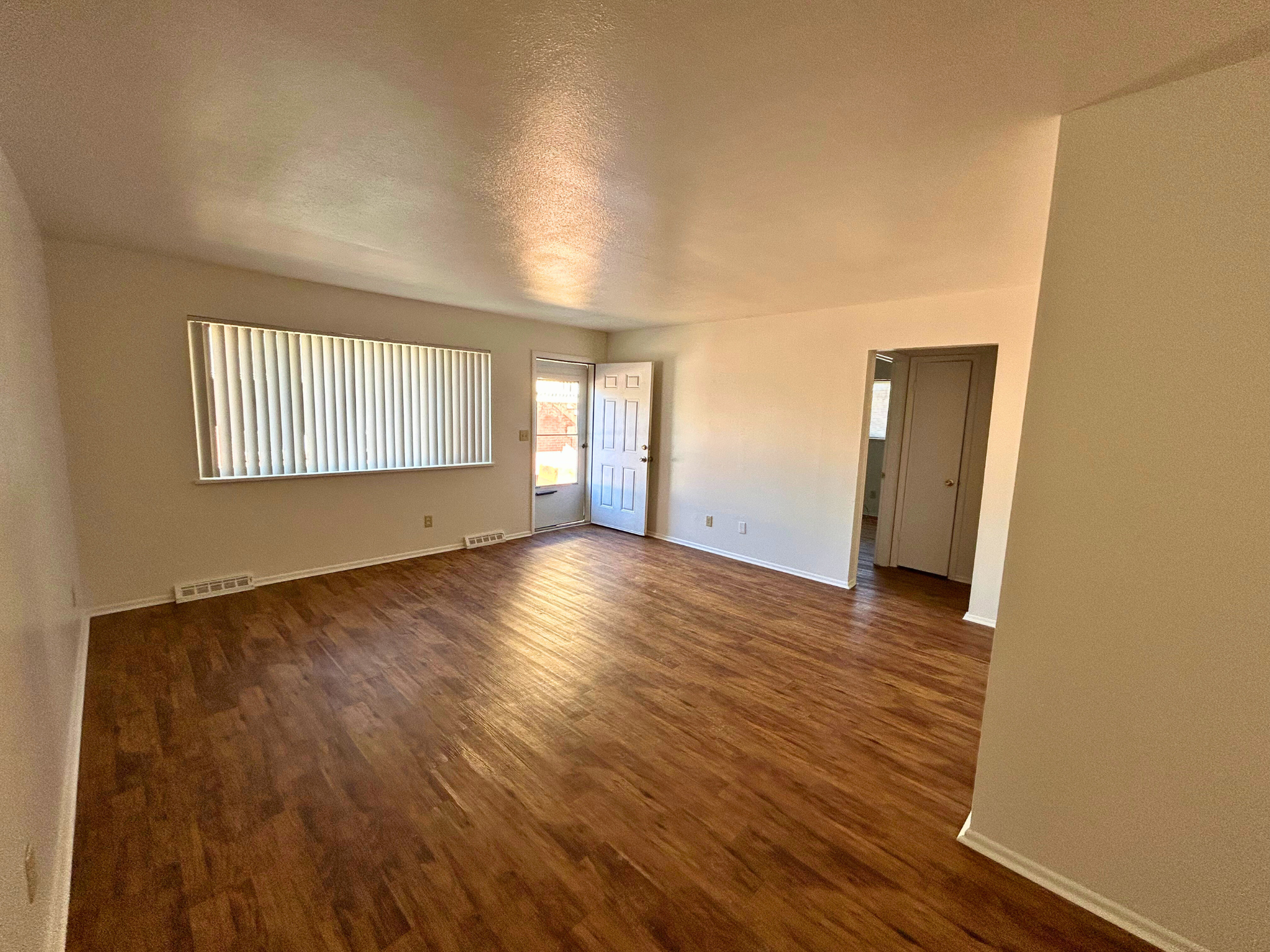 A room with wooden floors and a window with blinds.