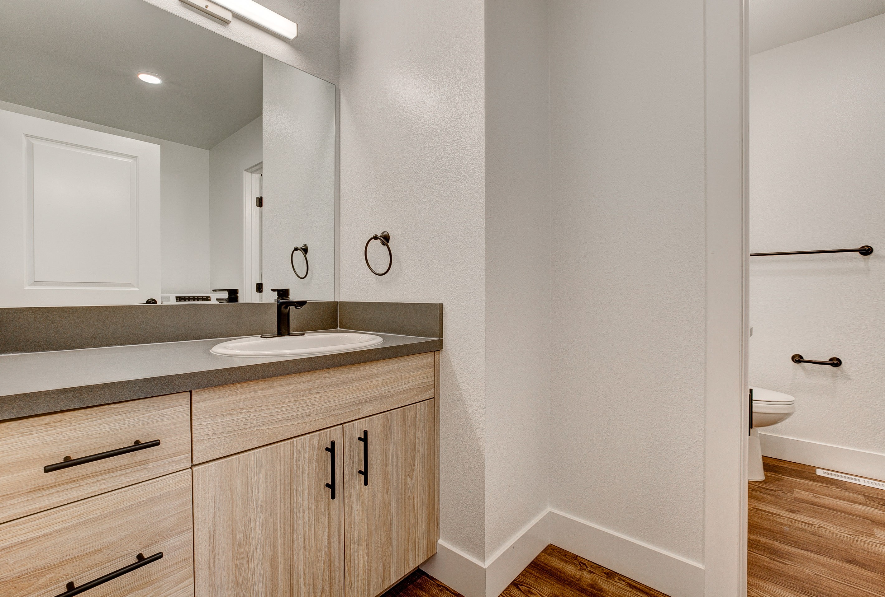 A bathroom with a sink, mirror, and wooden cabinets.