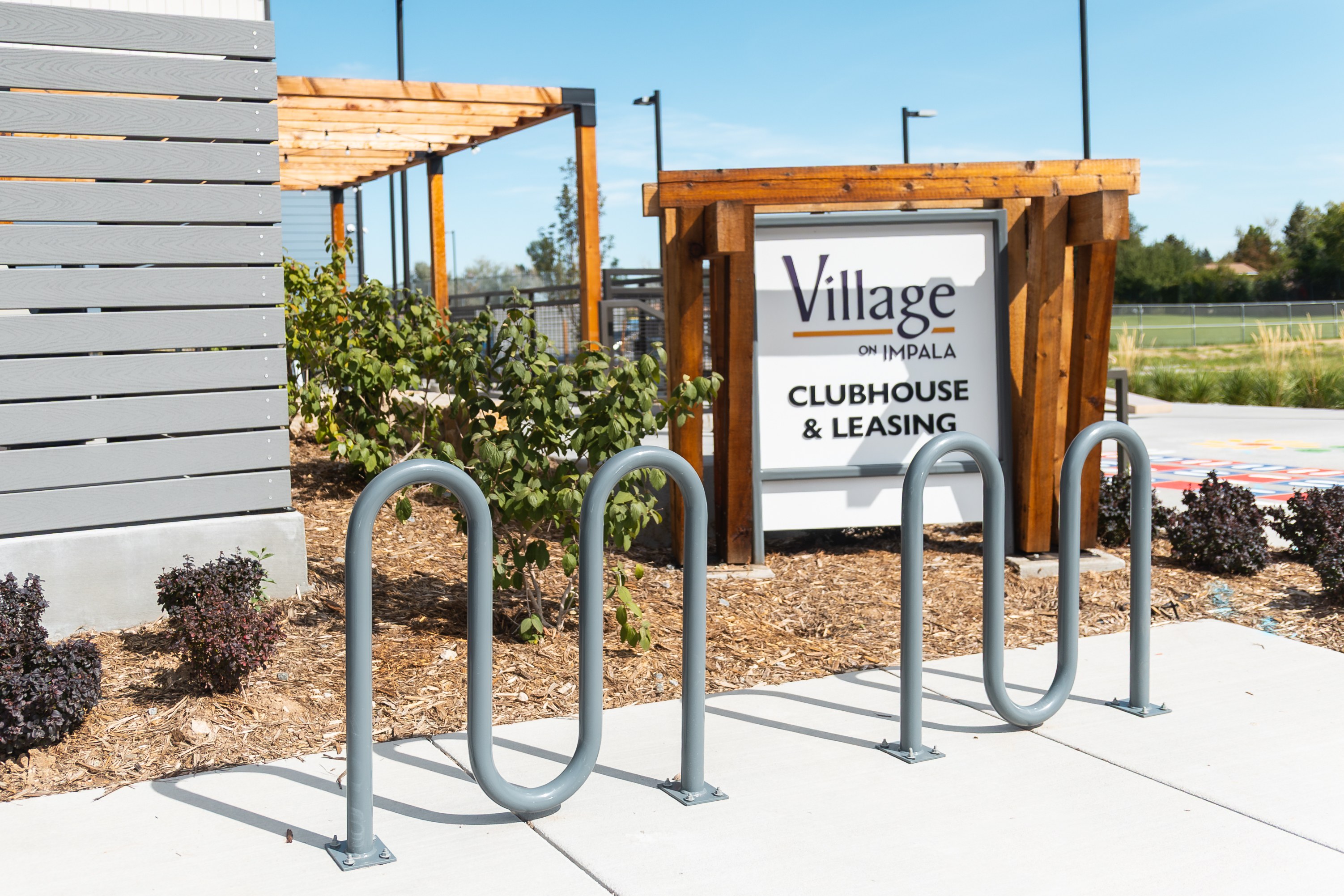 A sign for Village Clubhouse & Leasing stands in front of a building.