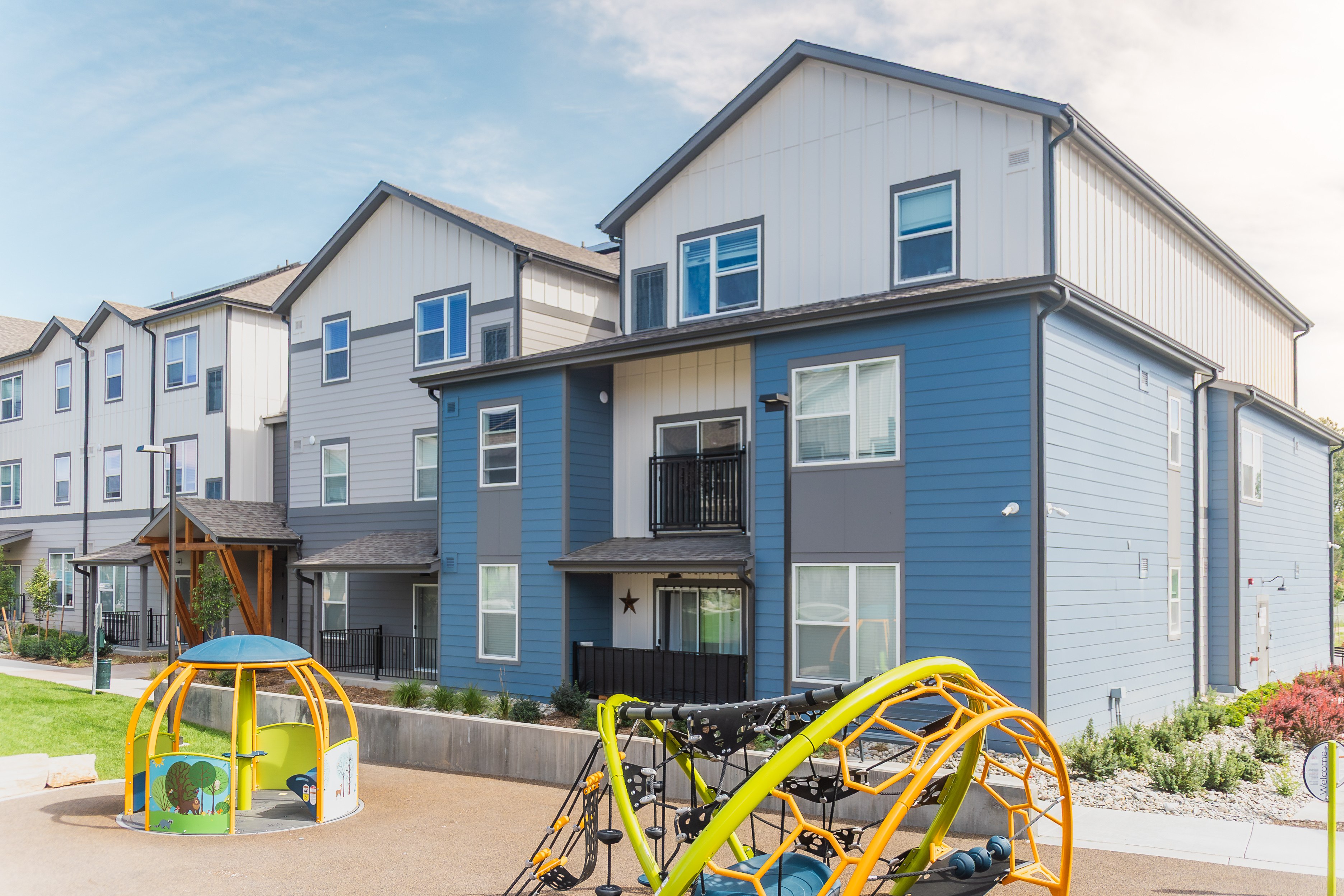 A playground with a swing set and a sandbox in front of a building.