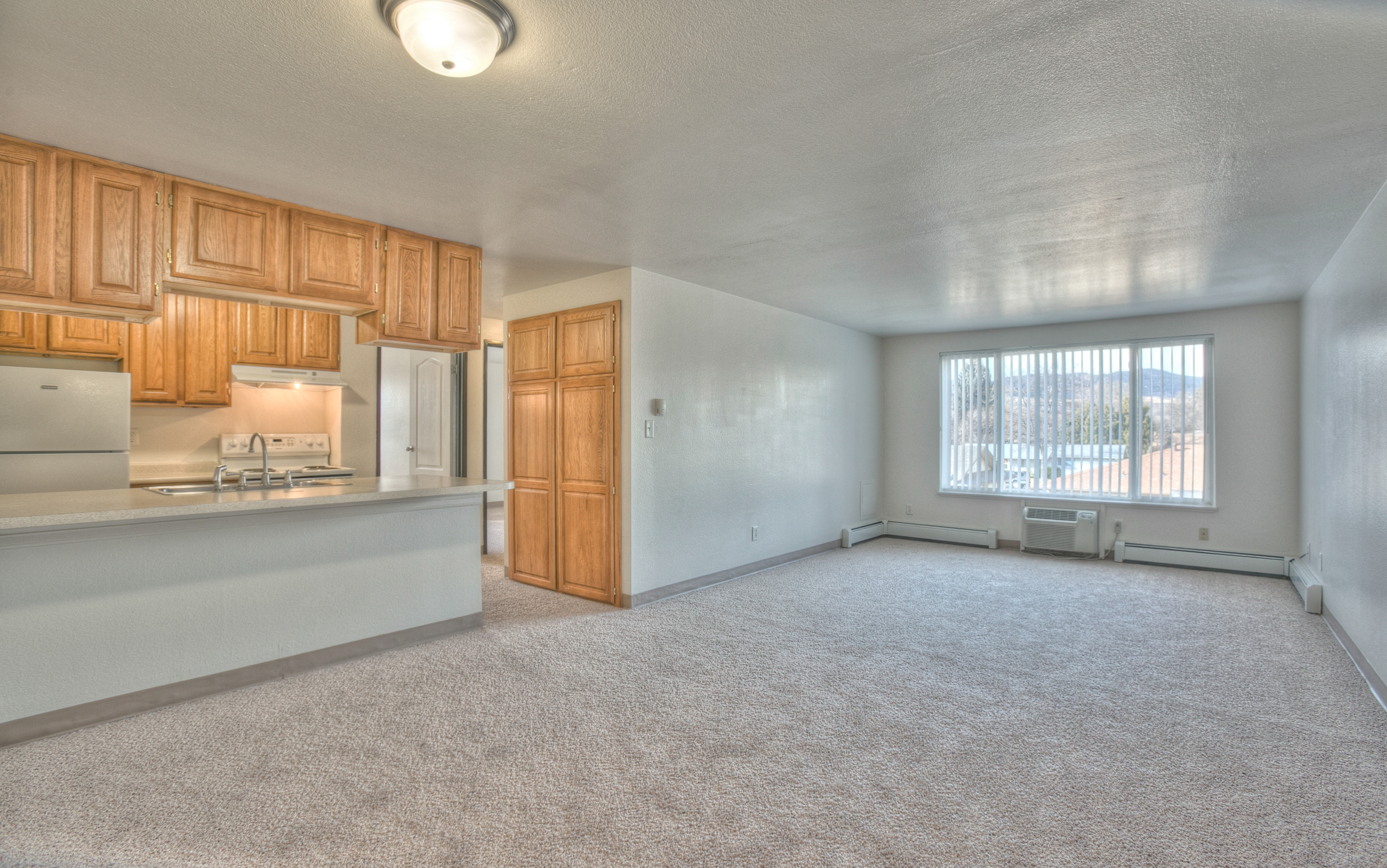 A room with wooden cabinets and a window with blinds.