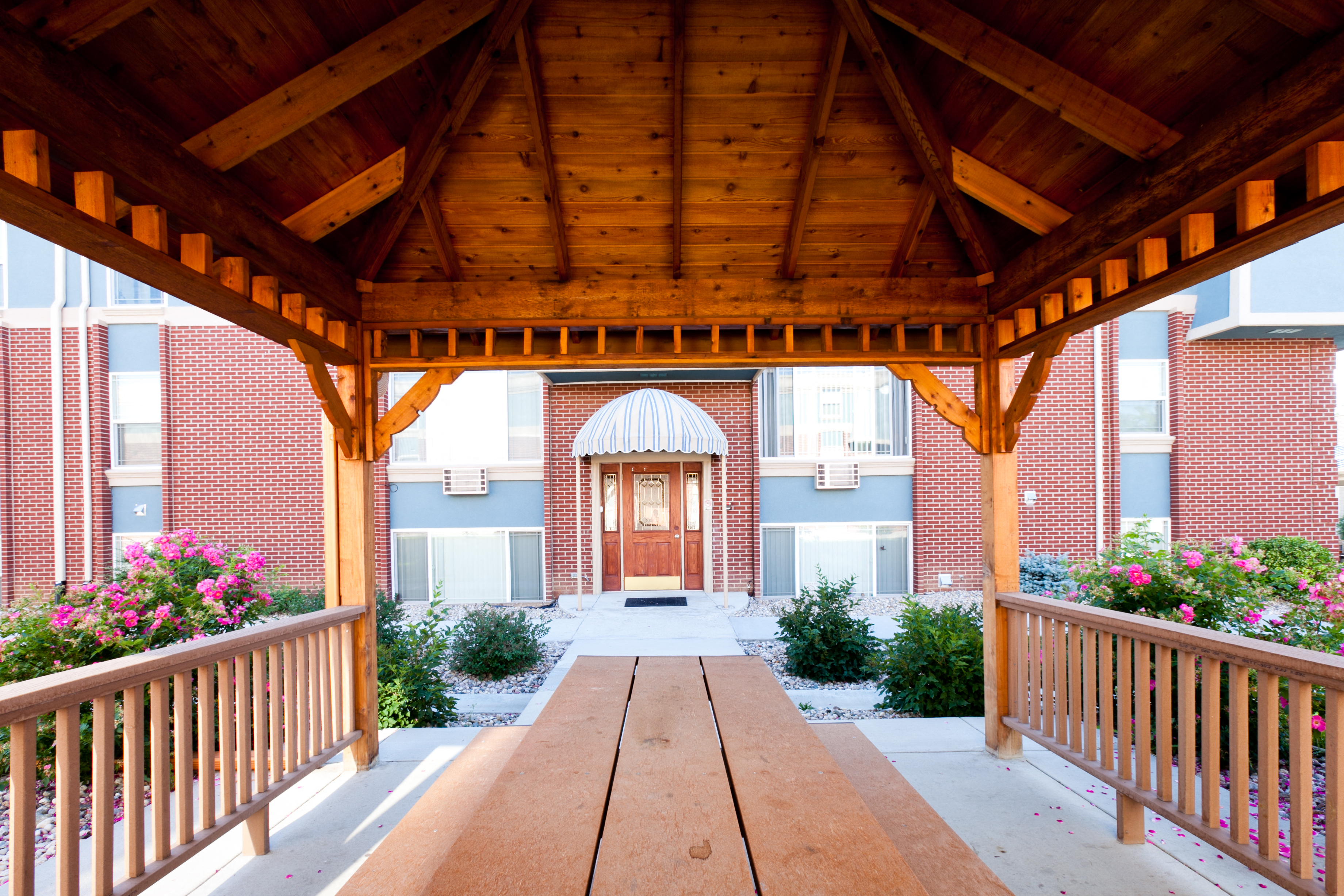 A wooden pavilion leads to a building with a dome.