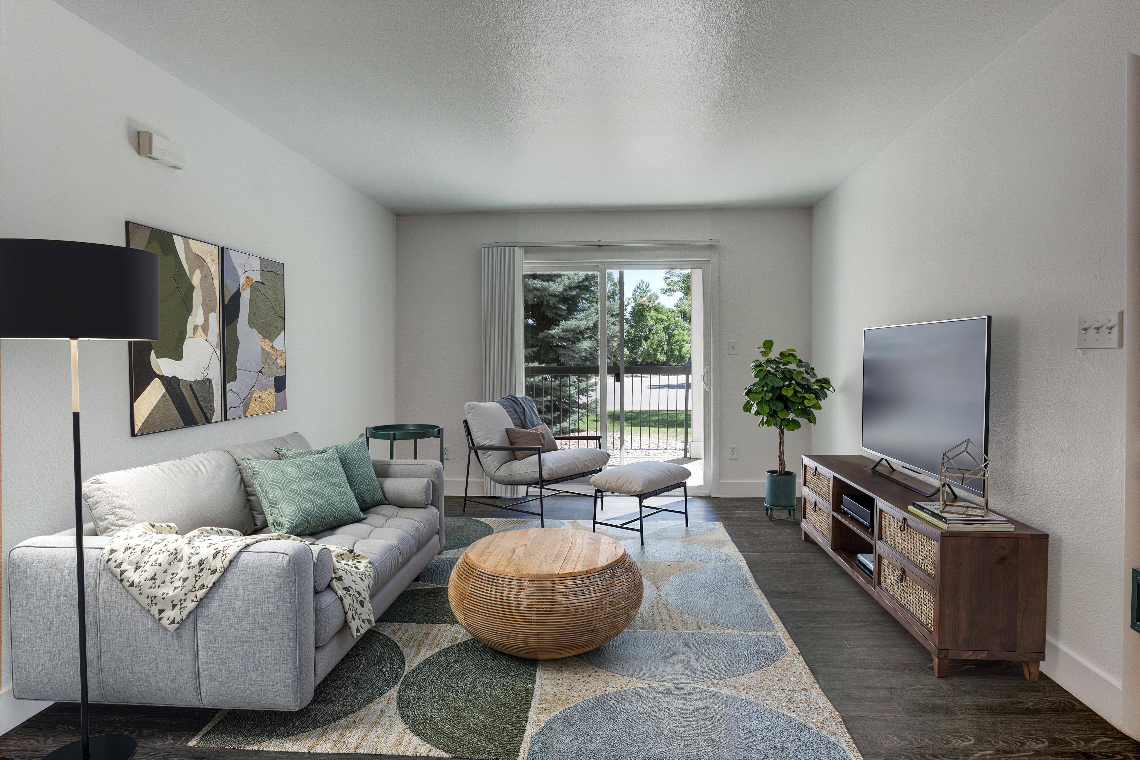 A living room with a grey couch, a wooden coffee table, a flat screen TV, and a large window.,A living room with a grey couch, a wooden coffee table, a flat screen TV, and a large window.
