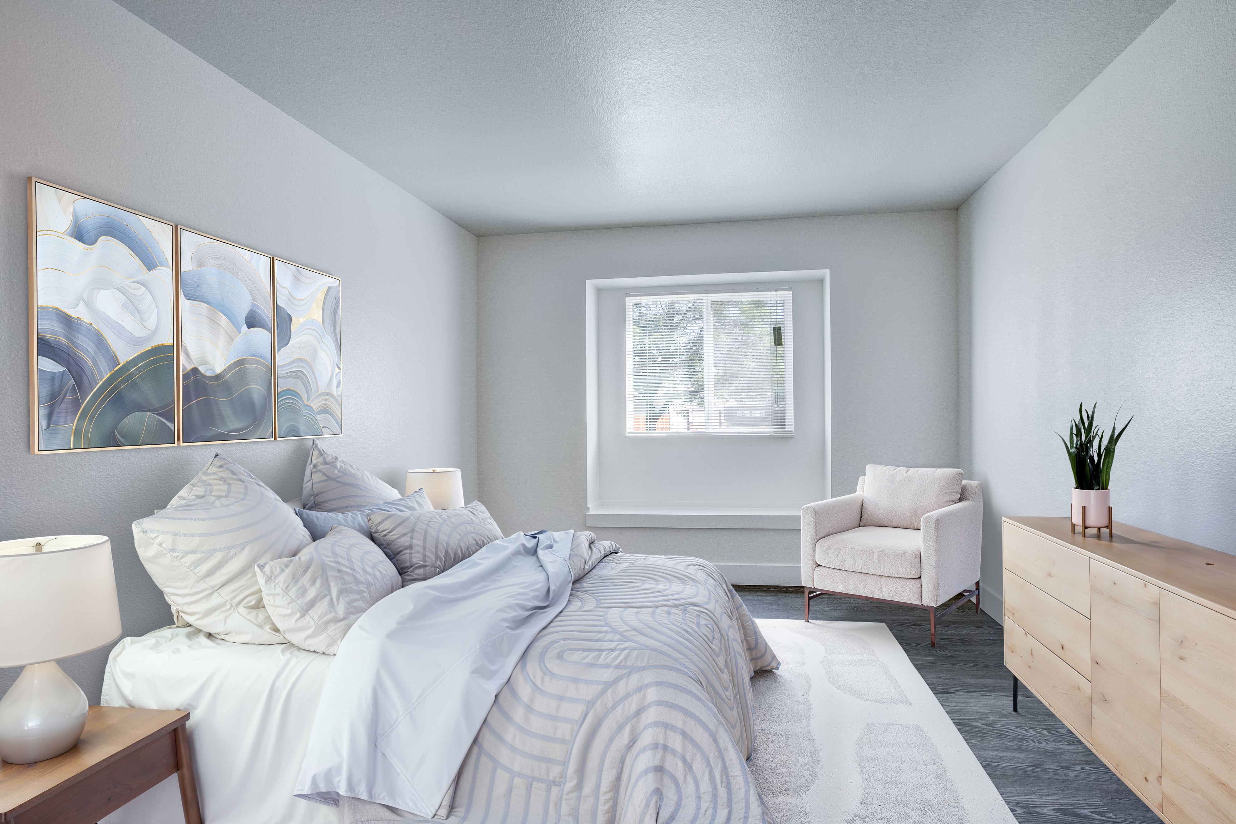 A bedroom with a large bed, a white chair, and a painting on the wall.,A bedroom with a large bed, a white chair, and a painting on the wall.