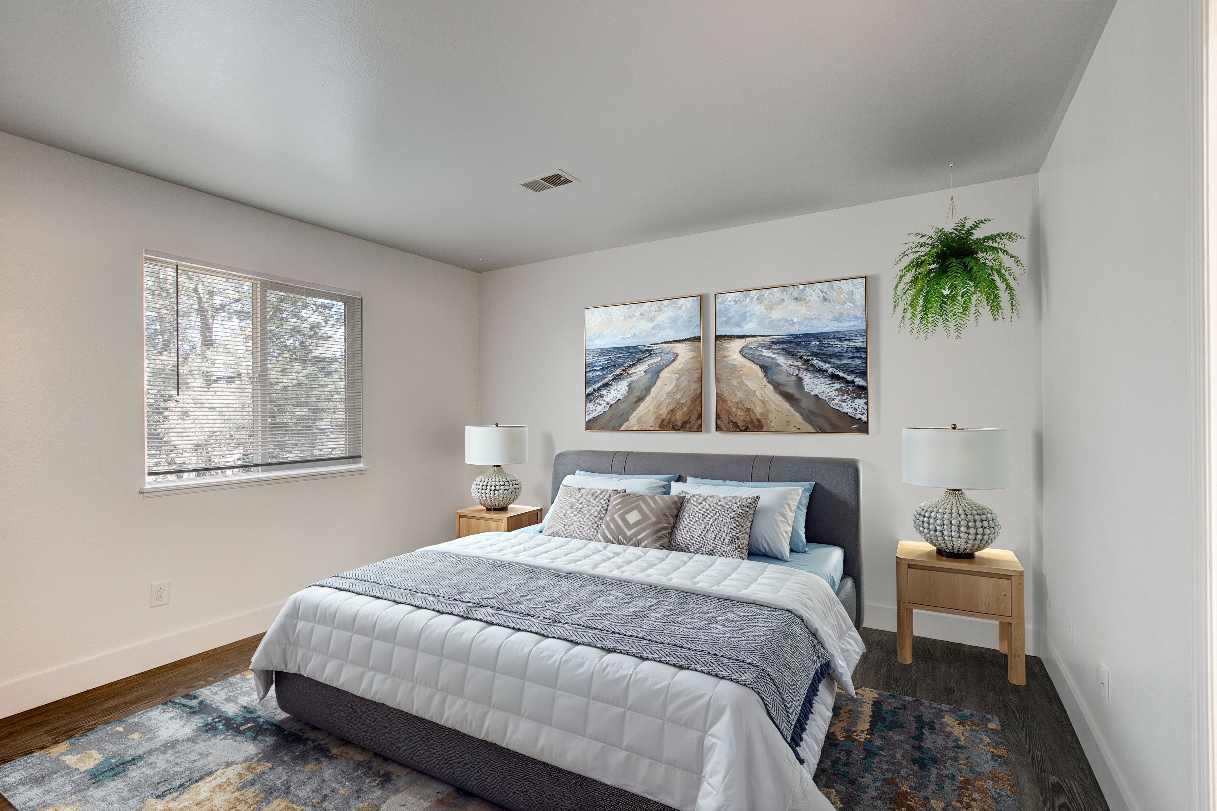 A bedroom with a large bed and a painting on the wall.