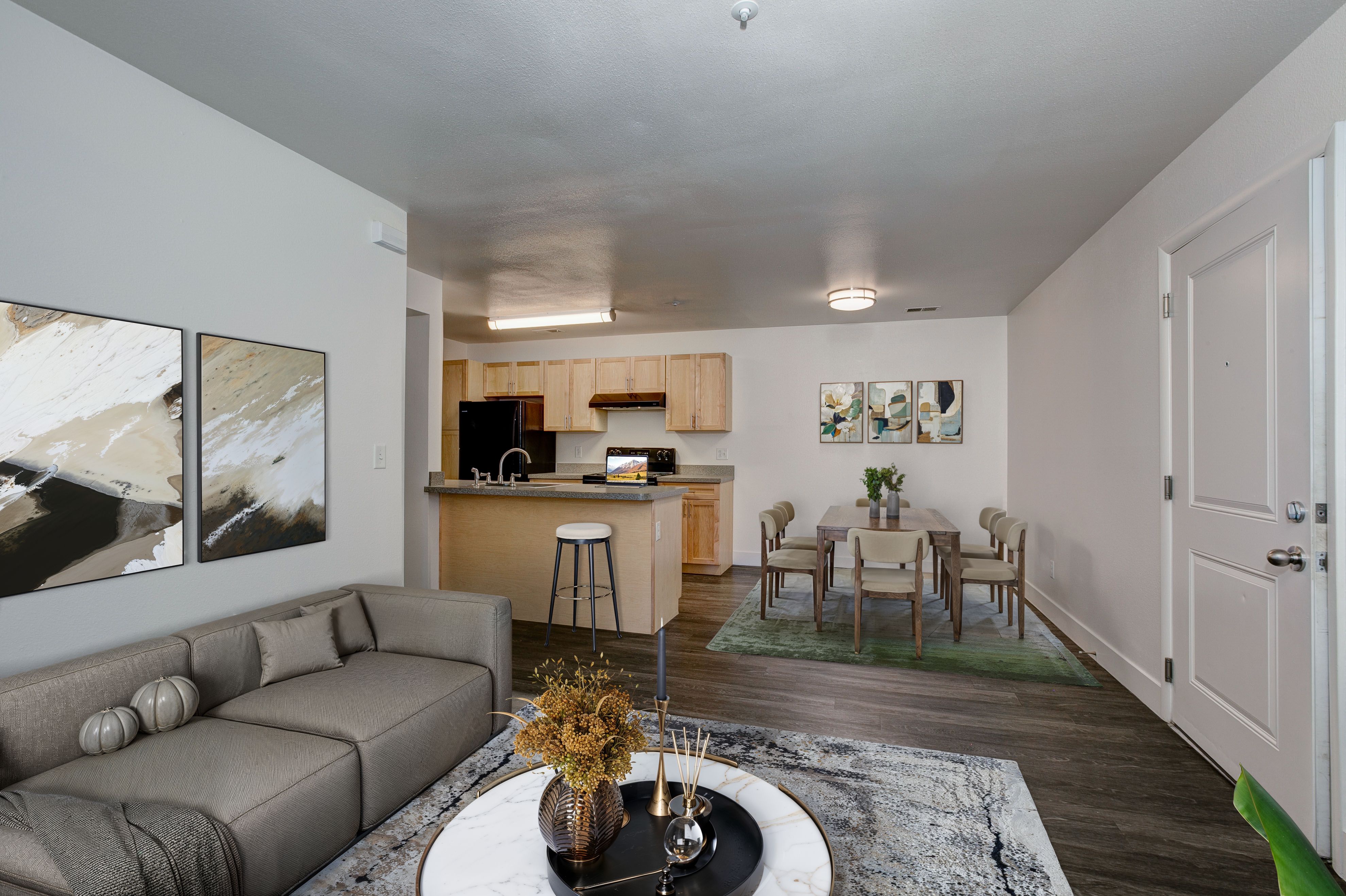 A modern living room with a grey sofa and a coffee table with a vase of flowers on it.