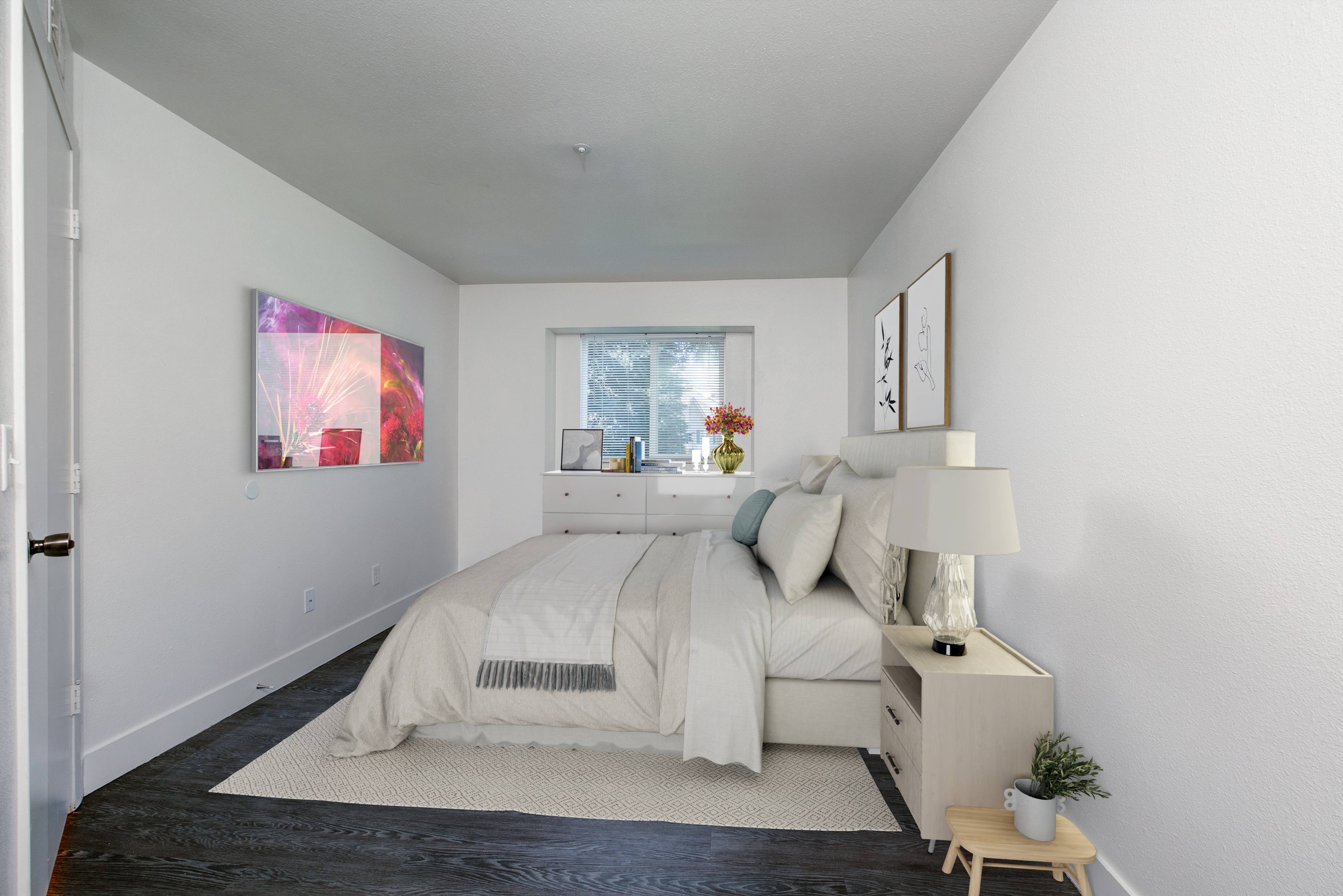 A bedroom with a large bed and a small table with a plant on it.