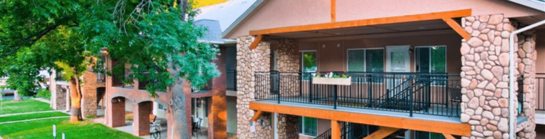 A building with a balcony and a tree in front of it.