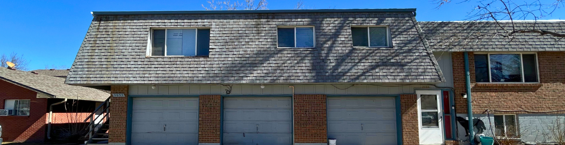 A house with a grey roof and a white garage door.