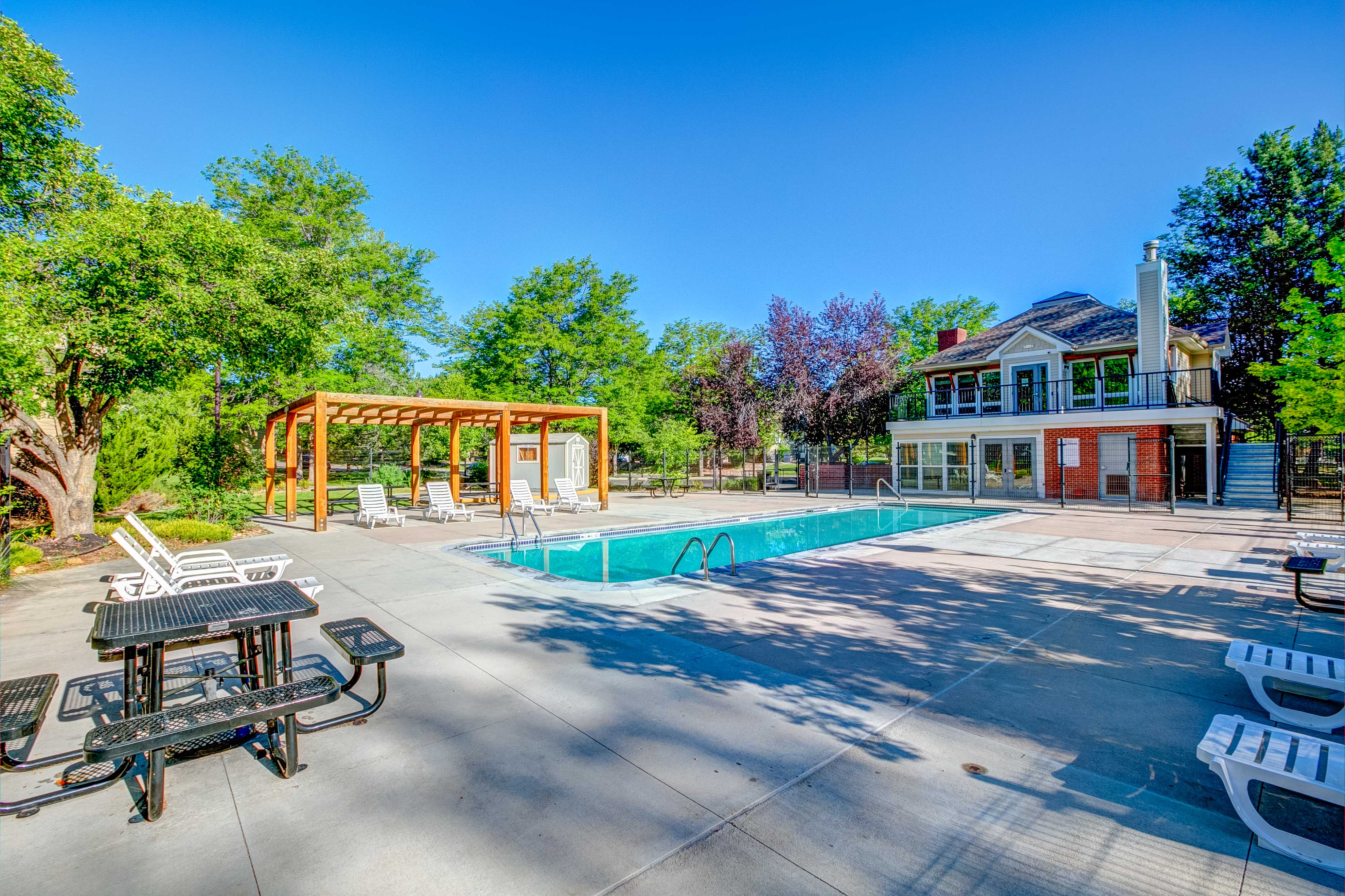 A pool area with a table and chairs and a house in the background.