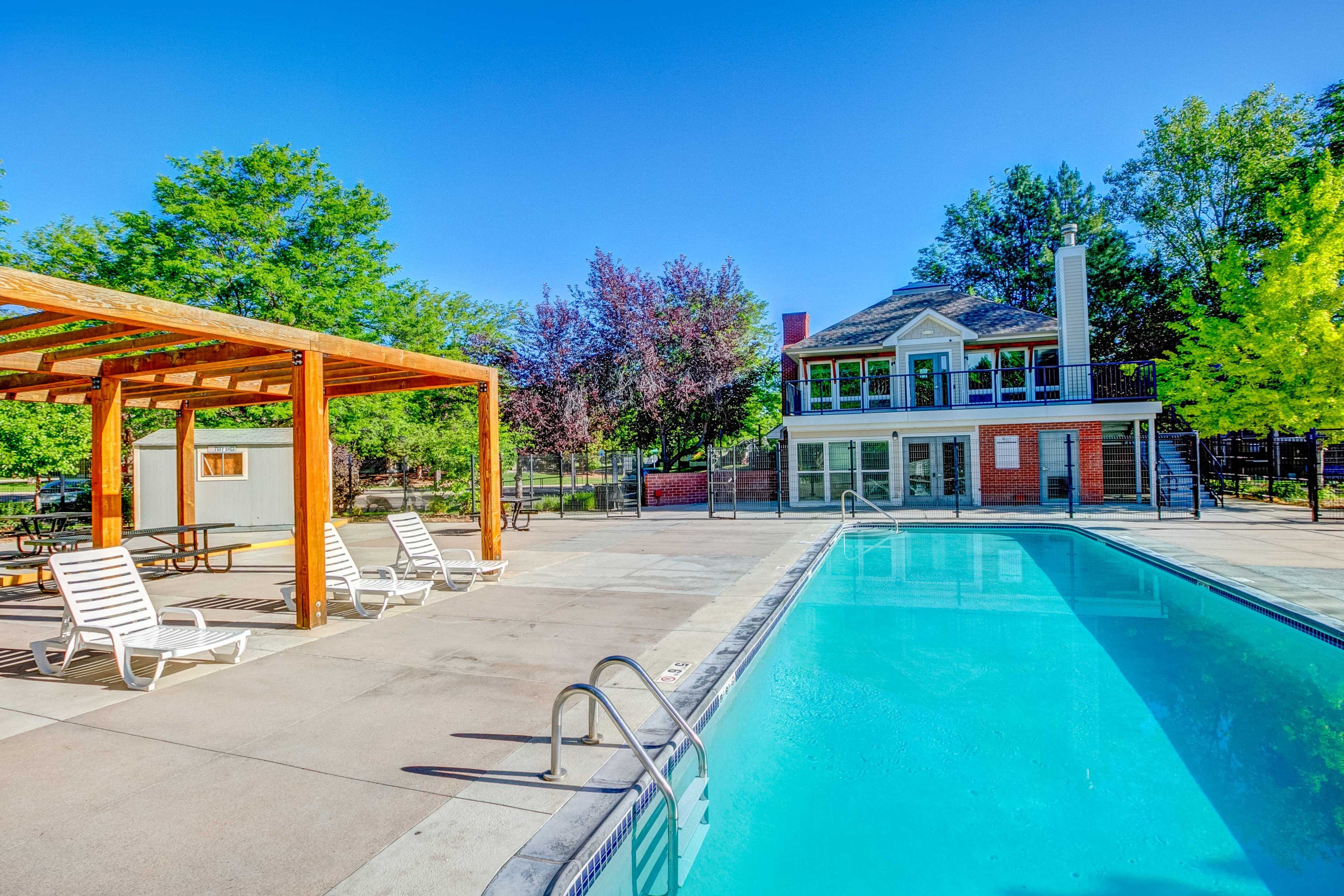 A large swimming pool with a wooden pavilion and sun loungers.