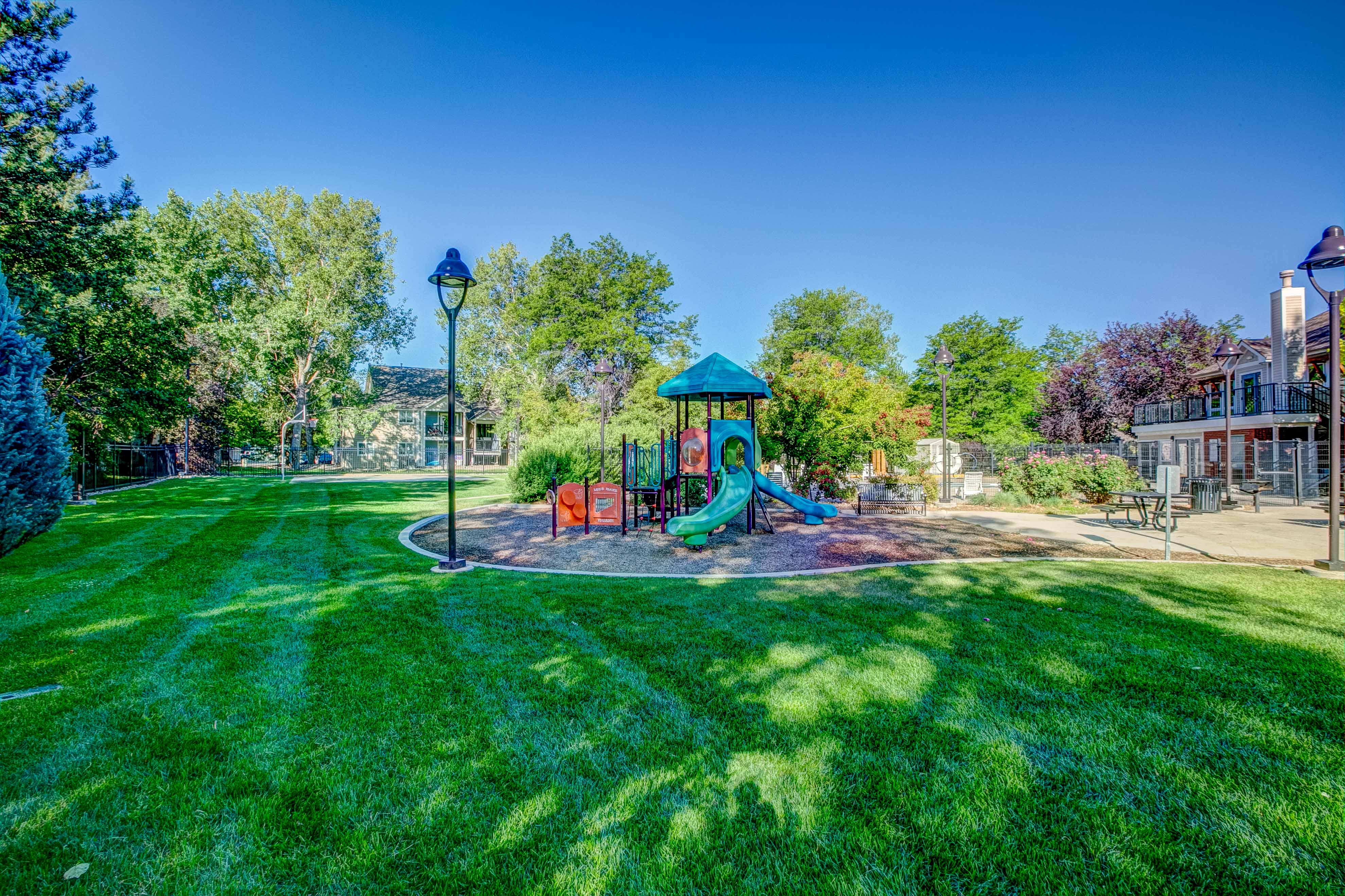 A playground with a green slide and a blue and white striped slide.