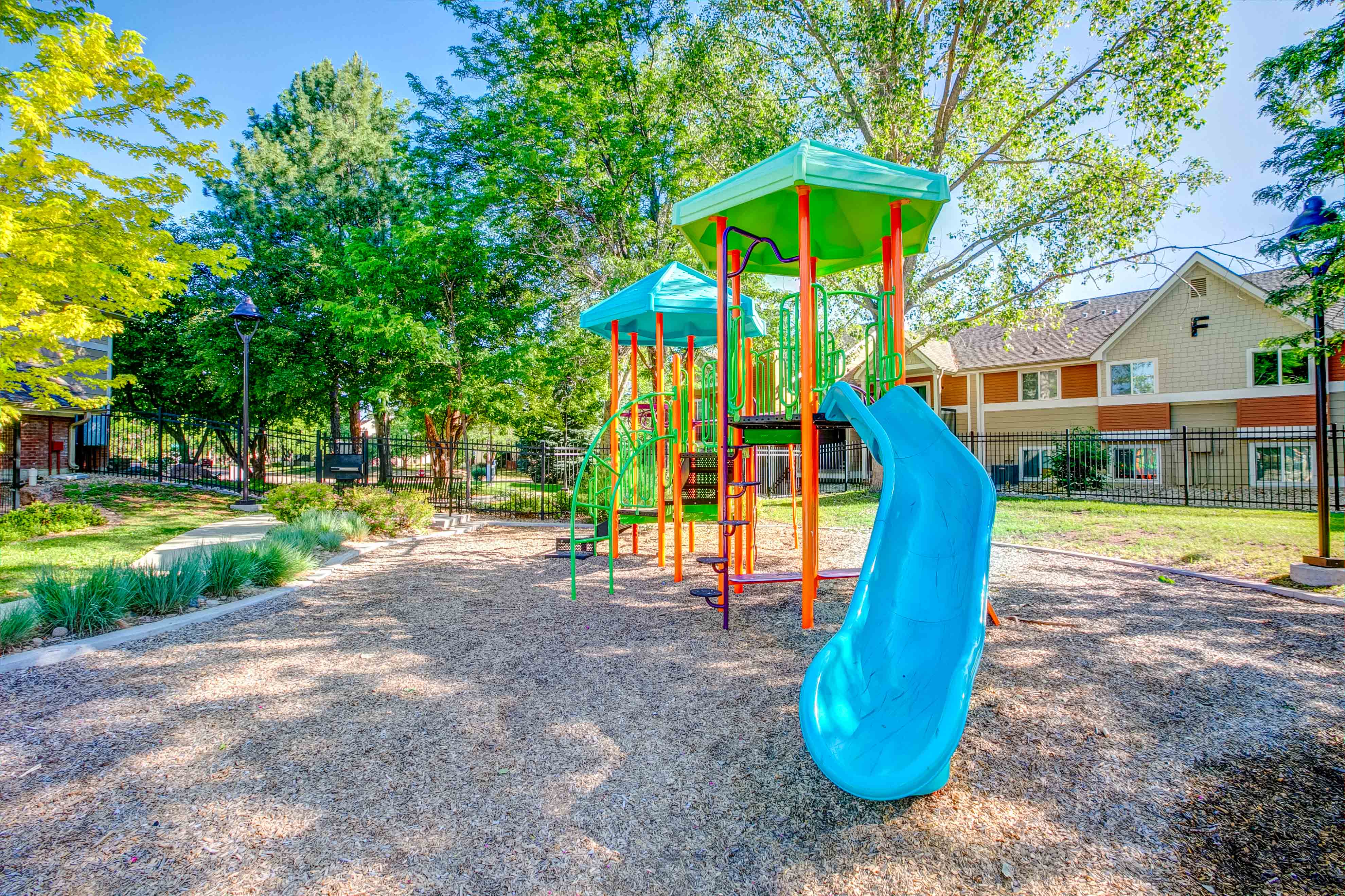 A playground with a blue slide and a green roof.