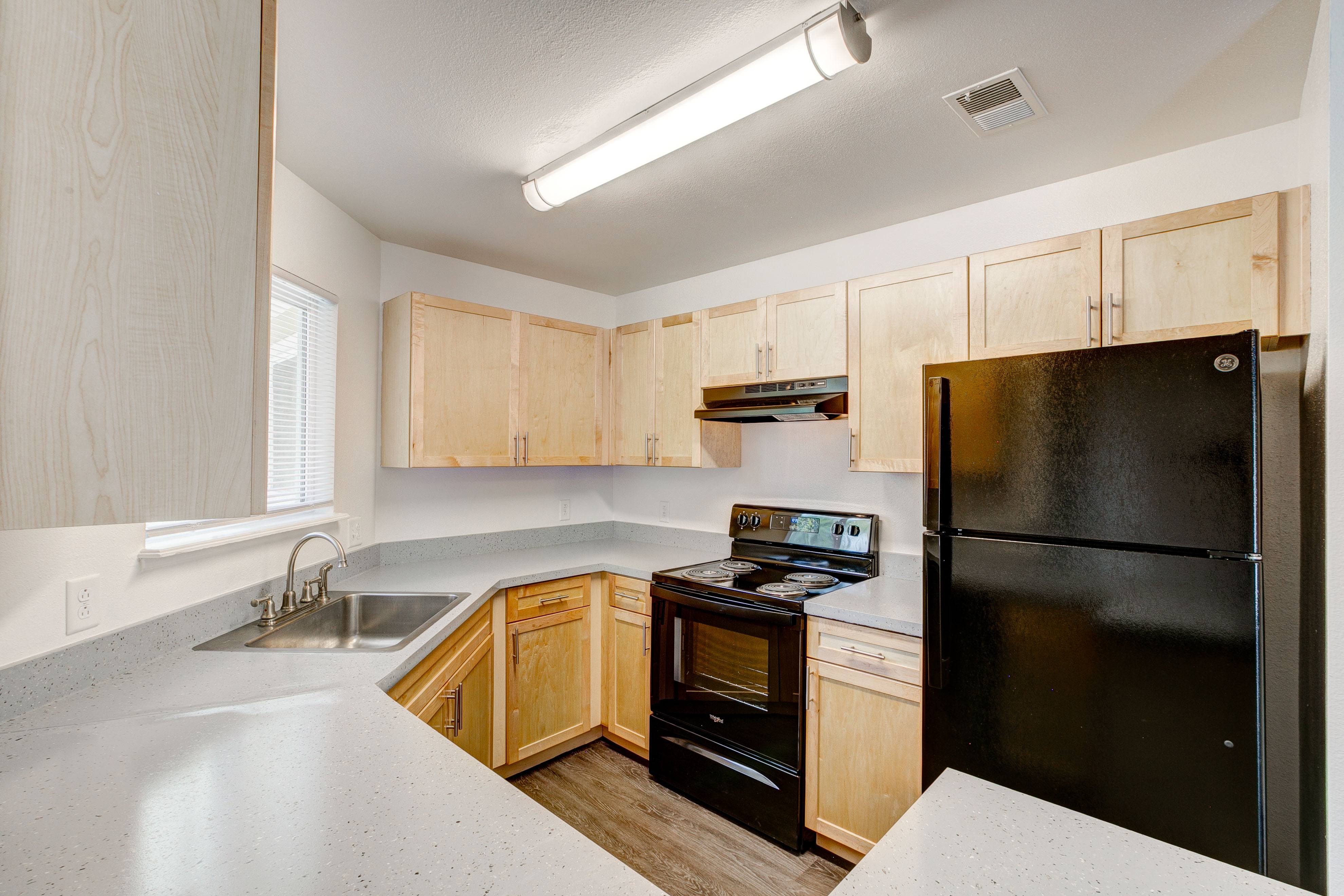 A kitchen with wooden cabinets and a black refrigerator.