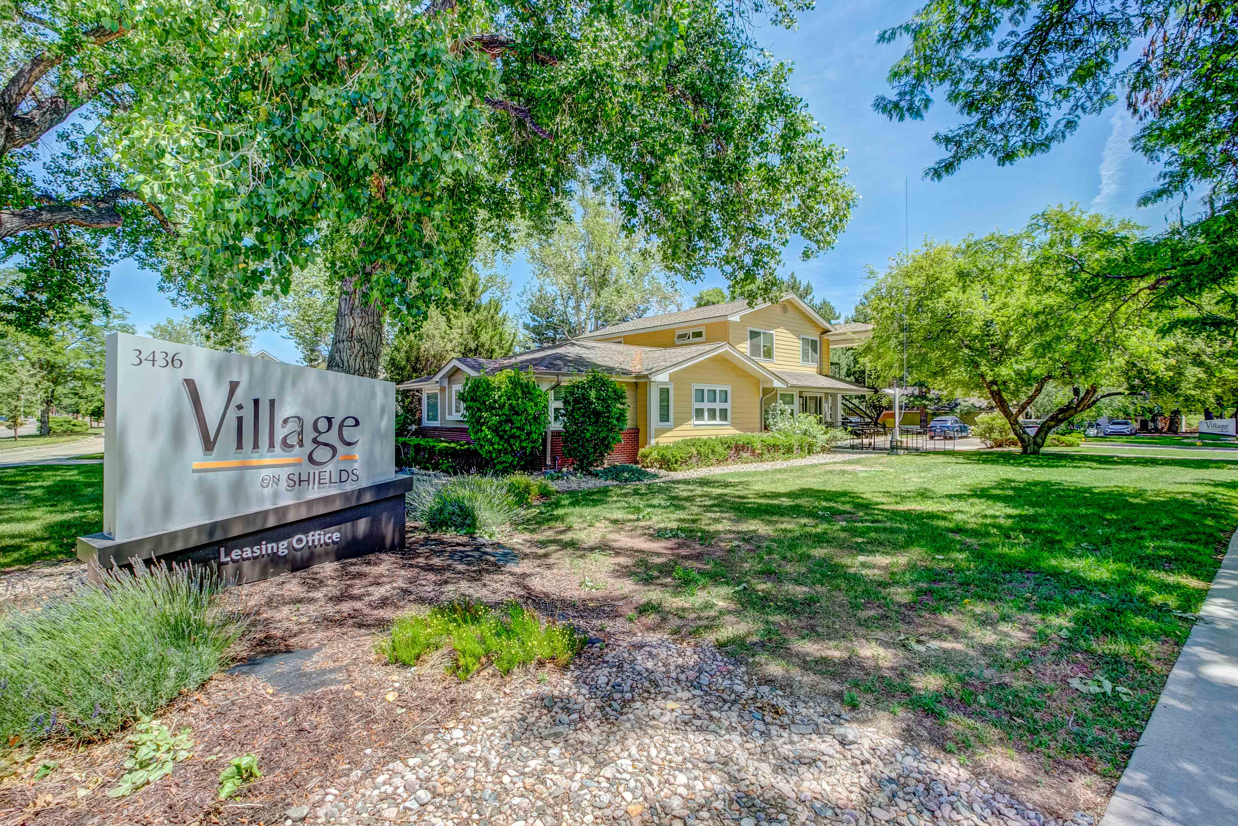 A sign for Village on Shields Leasing Office in front of a house.