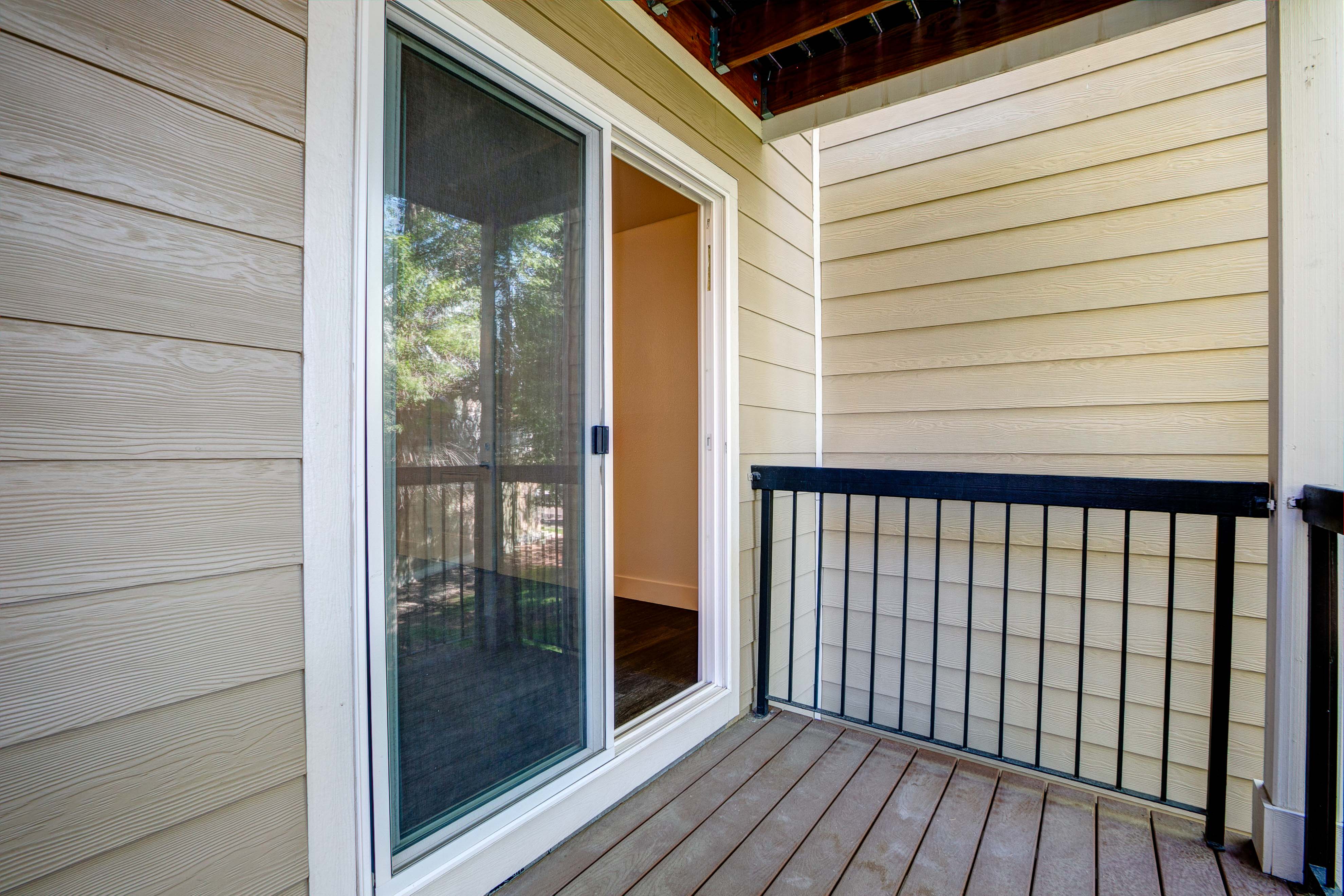A balcony with a glass door and a black railing.
