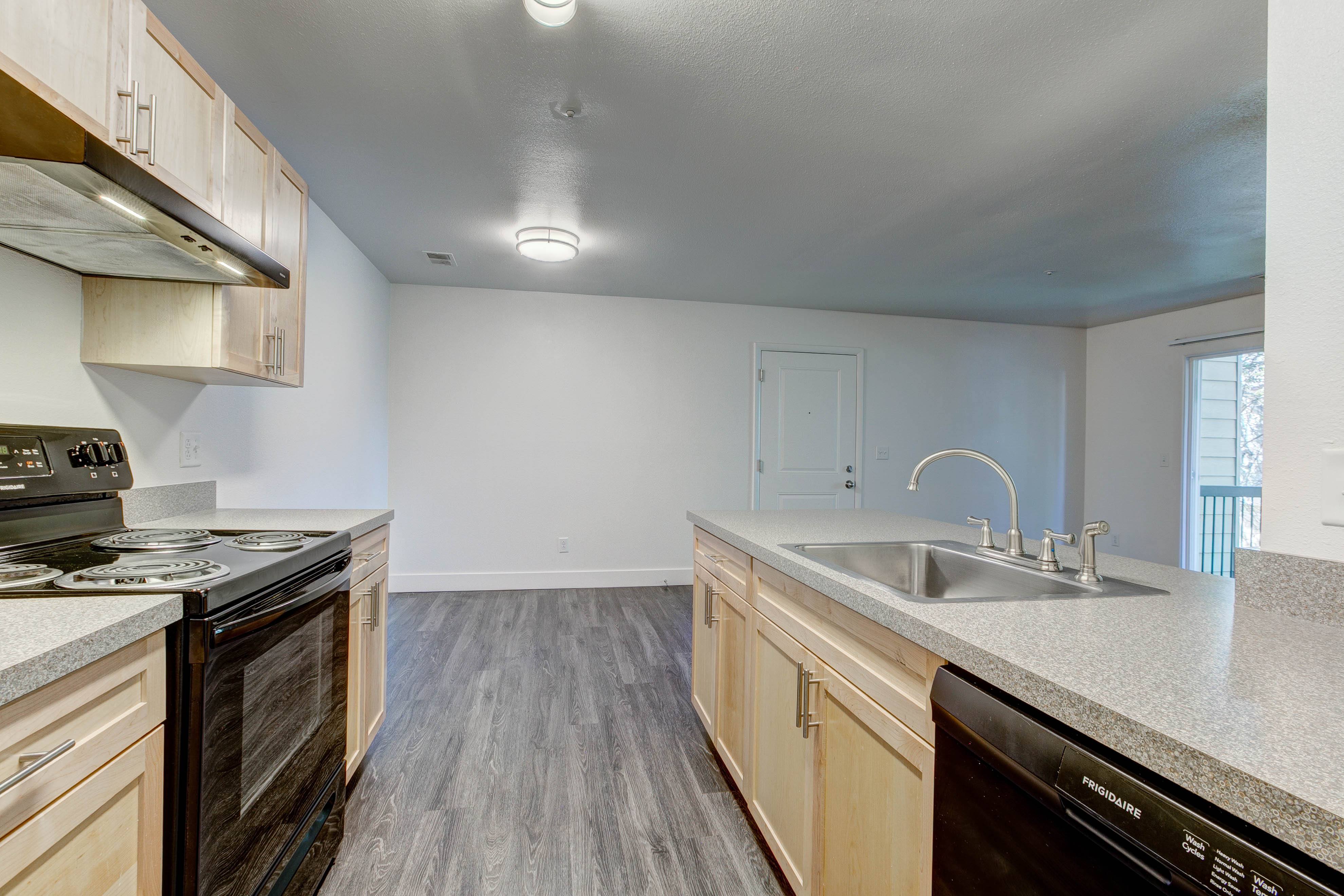 A kitchen with a stove, sink, and cabinets.