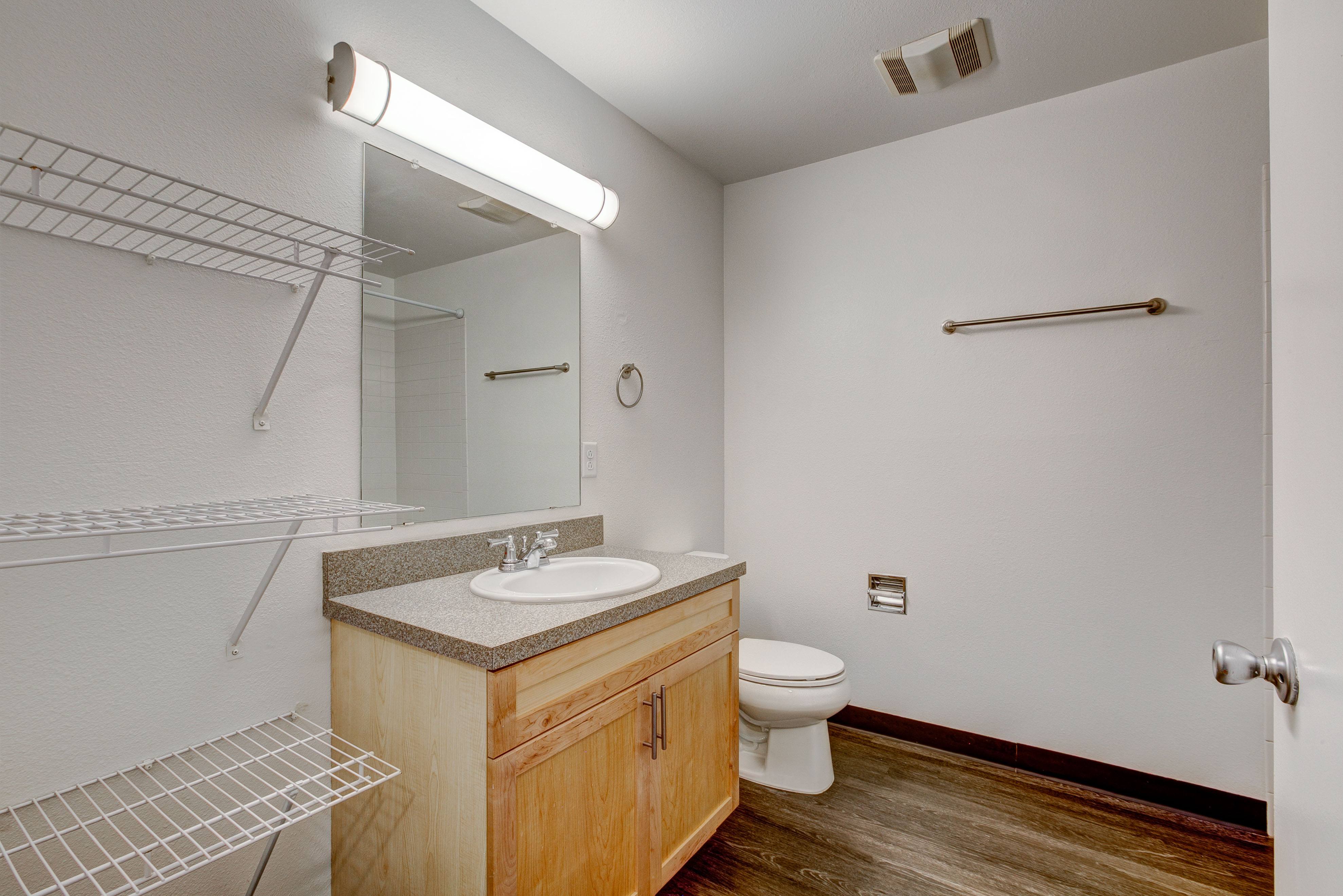 A bathroom with a toilet, sink, and mirror.