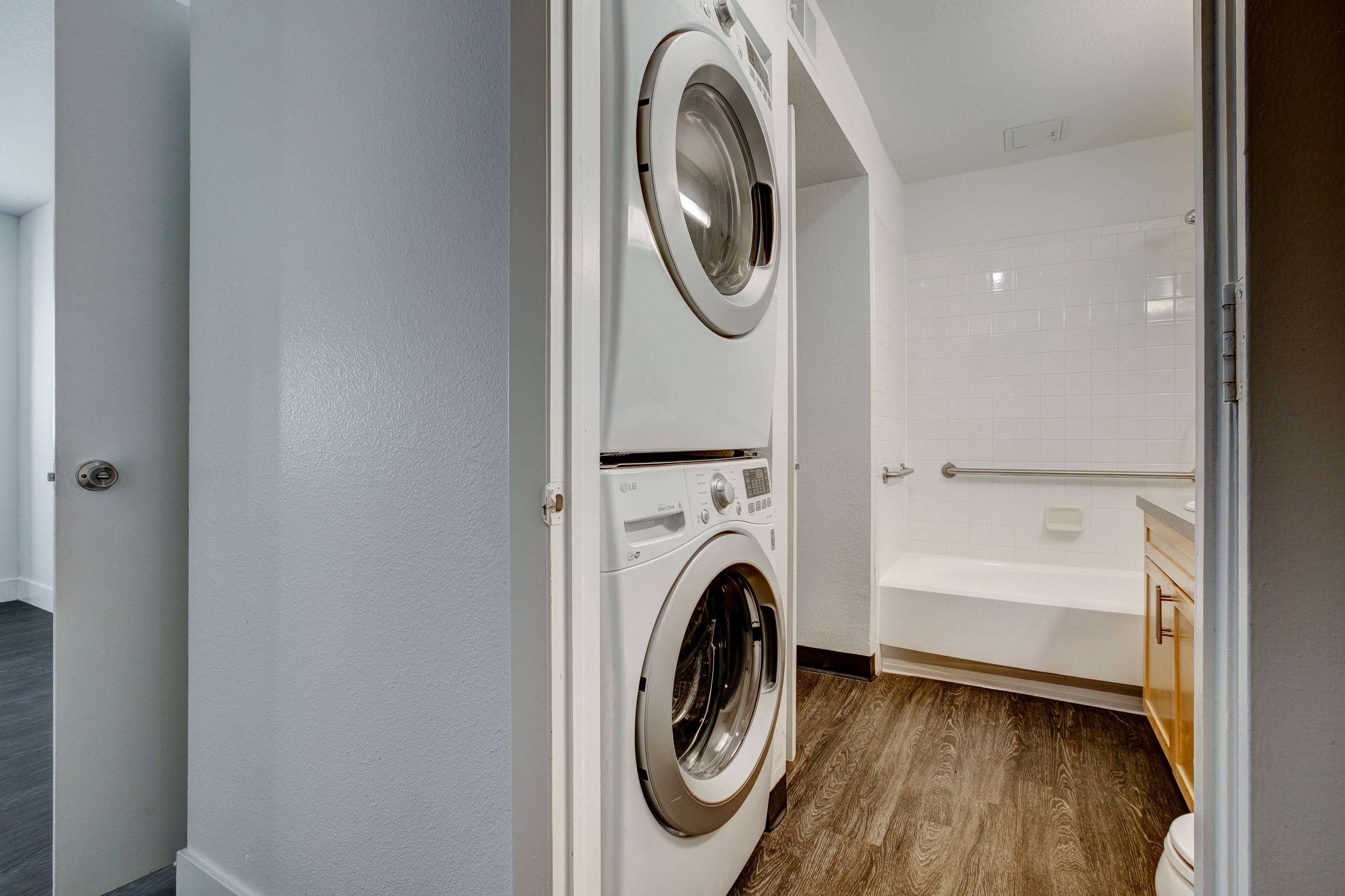 A white washing machine is in a small laundry room.,A white washing machine is in a small laundry room.