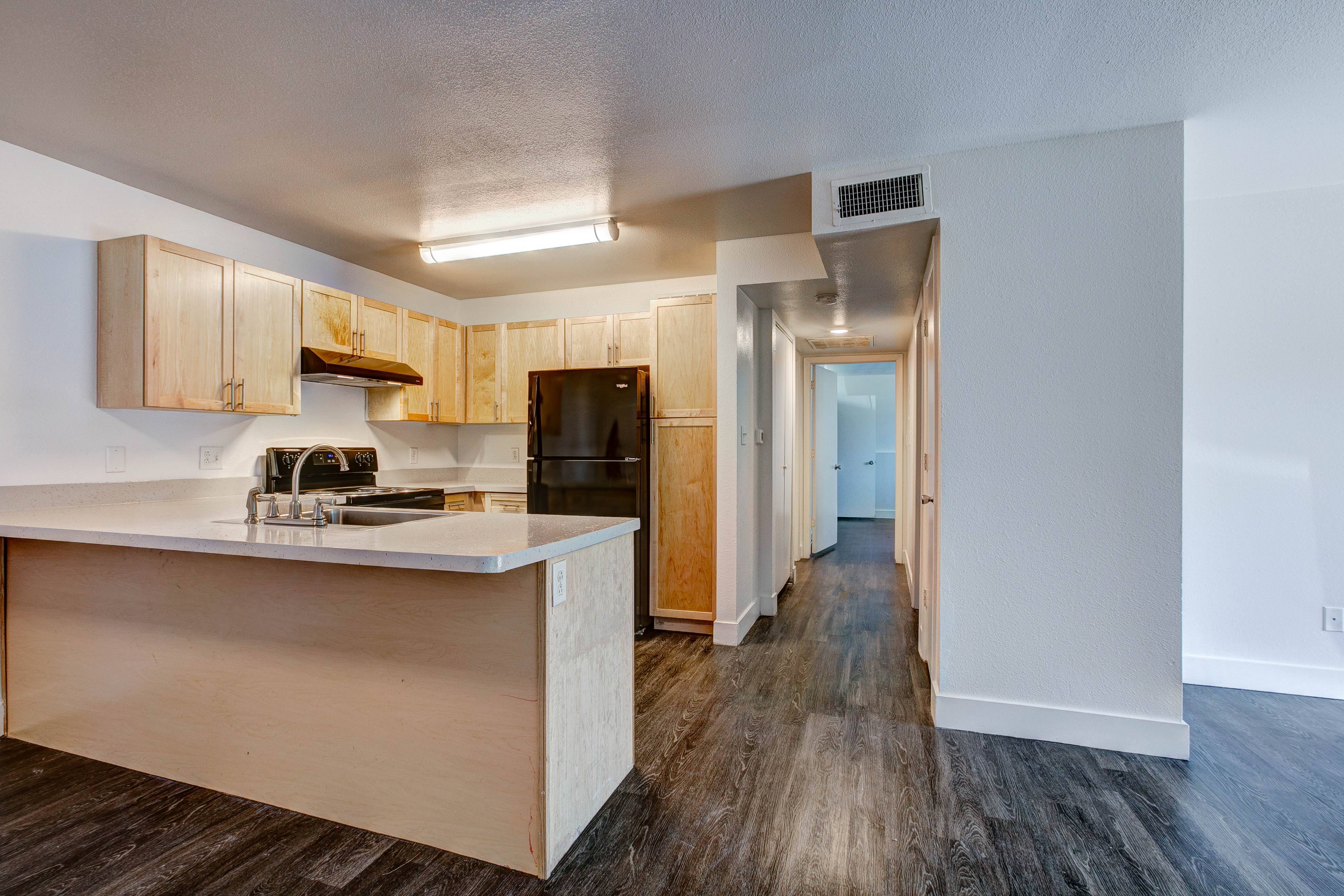 A kitchen with wooden cabinets and a white countertop.,A kitchen with wooden cabinets and a white countertop.